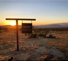 Load image into Gallery viewer, a wooden bench sitting in the middle of a field